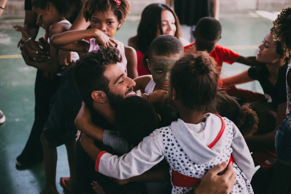 Adulto abrazando con cariño a un grupo de niños, reflejando un vínculo afectivo cercano